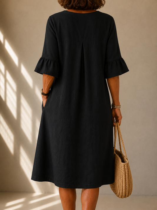 Back view of the Frances dress in Black, showing the box pleat and the ruffled three-quarter sleeves