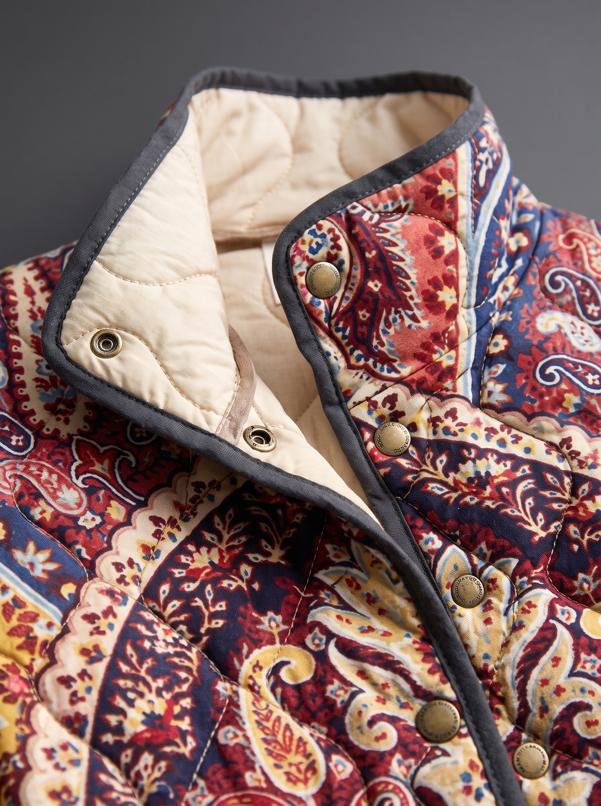 Close view of the stand collar, brass snaps and cream quilted lining on the Lorena jacket
