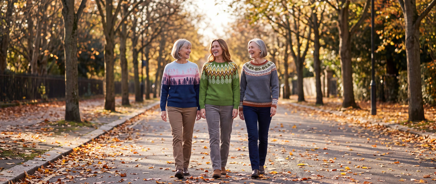 Three women walking a tree-lined street in autumn, wearing folk knit sweaters from The Heritage Knitwear Edit
