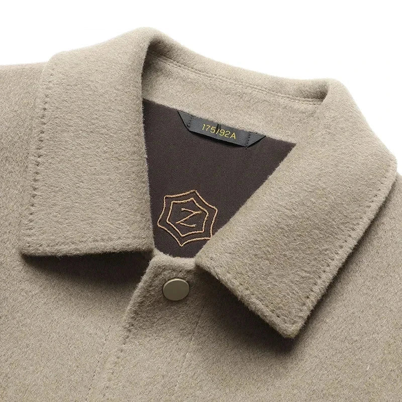 Close view of the spread collar and tonal snap button on the beige jacket