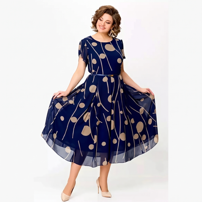Woman wearing the Marjorie navy polka dot chiffon midi dress, front view, holding the pleated skirt out