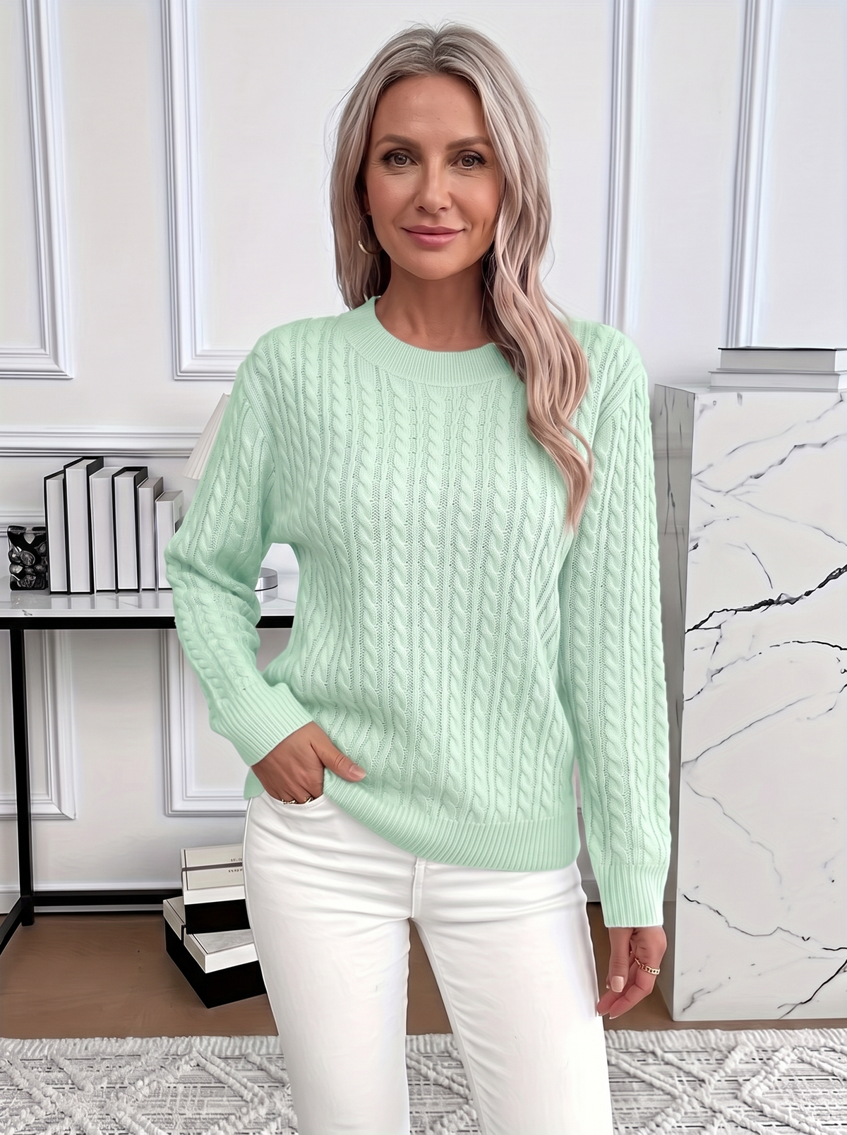 Woman wearing the Evelyn cozy cable knit sweater in mint green with white trousers