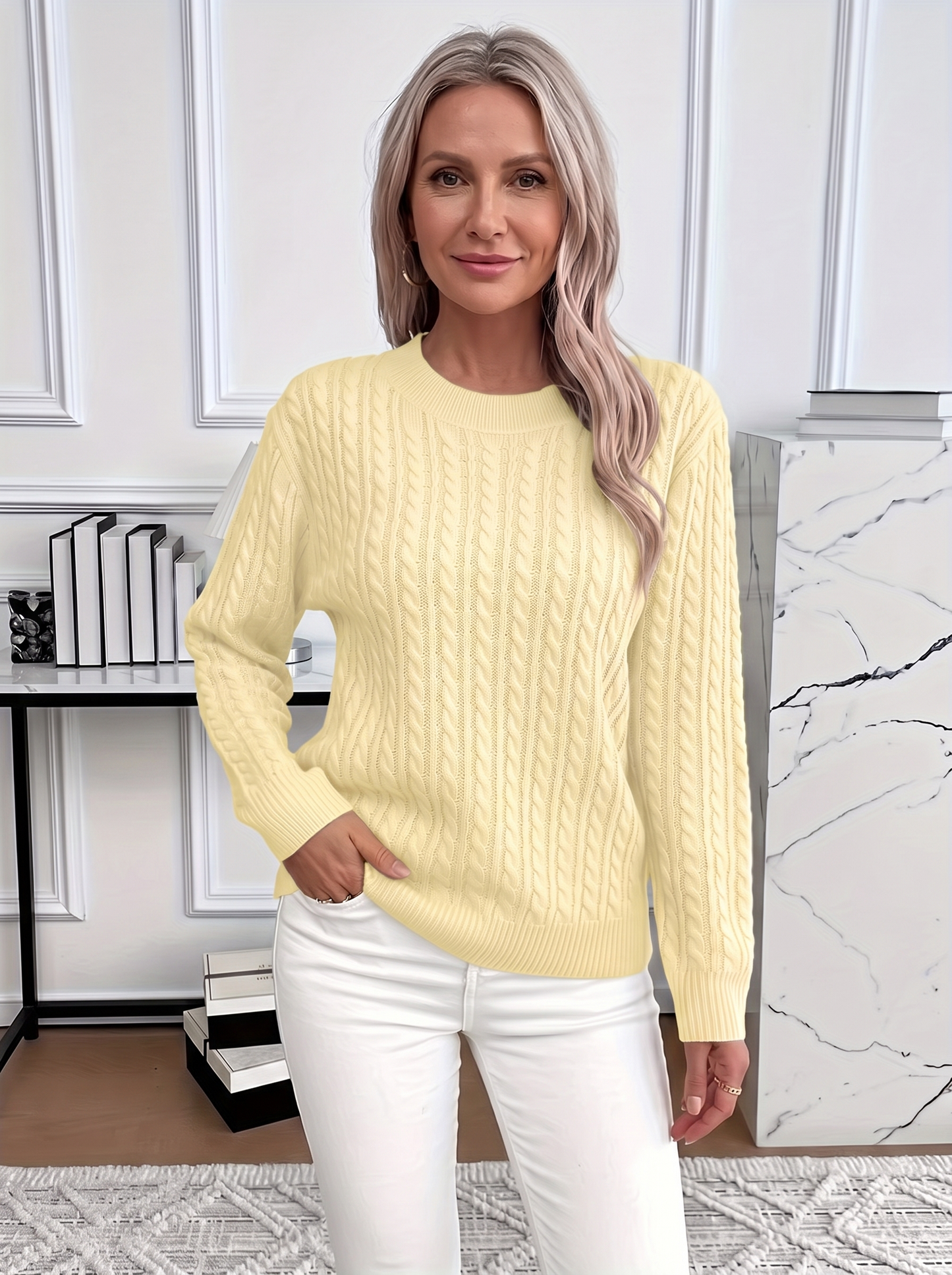 Woman wearing the Evelyn cozy cable knit sweater in pale yellow with white trousers