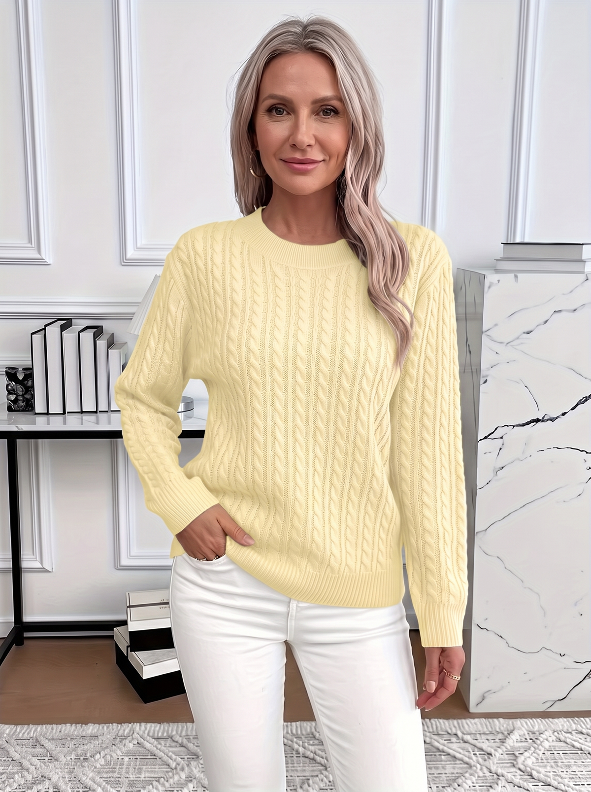 Woman wearing the Evelyn cozy cable knit sweater in pale yellow with white trousers