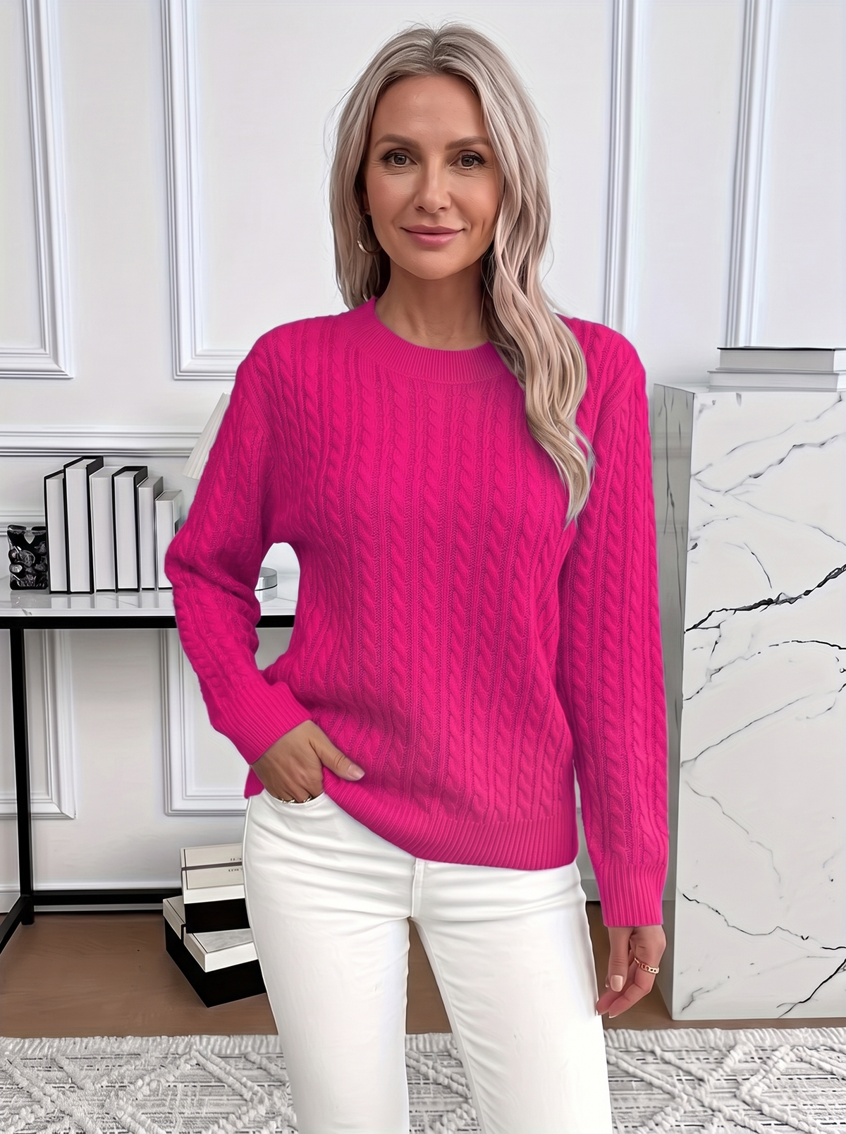 Woman wearing the Evelyn cozy cable knit sweater in fuchsia with white trousers