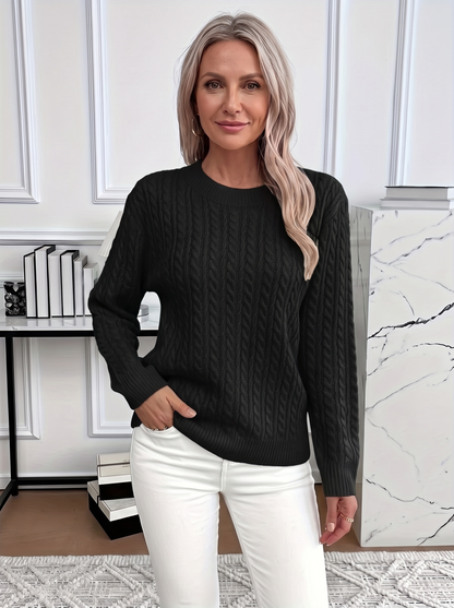 Woman wearing the Evelyn cozy cable knit sweater in black with white trousers