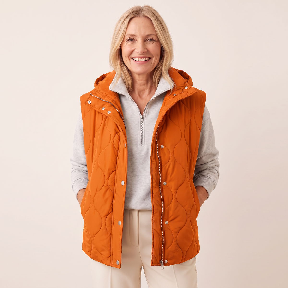 Ramona quilted hooded puffer vest in orange, showing the wave ogee quilt stitching and silver snap button placket