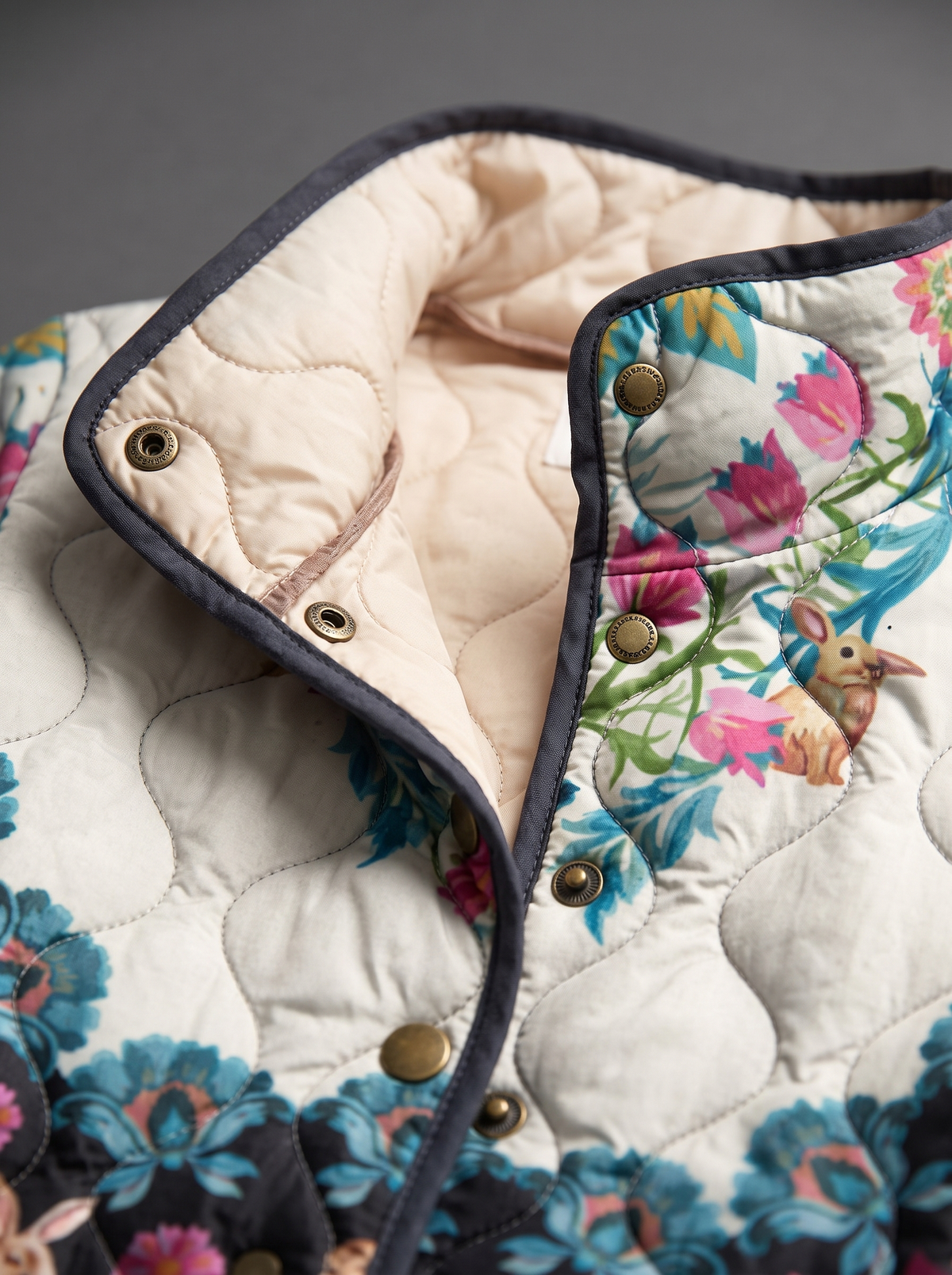 Close view of the stand collar, brass snaps and cream quilted lining on the Lydia jacket