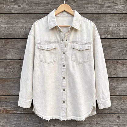Dottie raw hem denim jacket in white, shown on a wooden hanger against a weathered wood plank wall