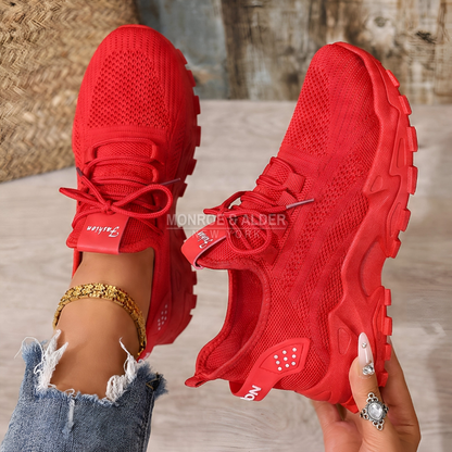 Molly sneaker in red, held in hand showing the lacing