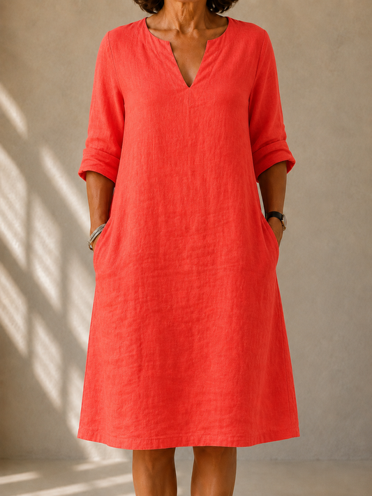 Marcella dress in Coral, front view showing the split V-neck and rolled sleeves