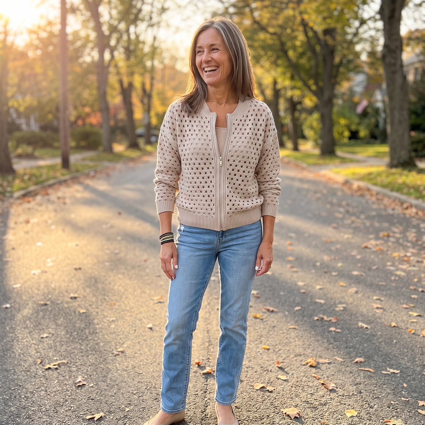 Yvette knitted cardigan in Beige, worn on a tree-lined street at autumn golden hour